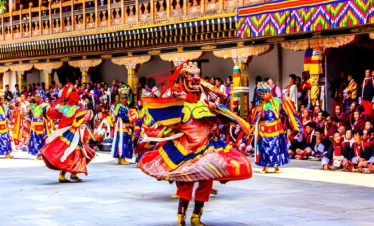 Traditional masked dance in Bhutan performed during Tshechu festival with colorful costumes and monastery courtyard